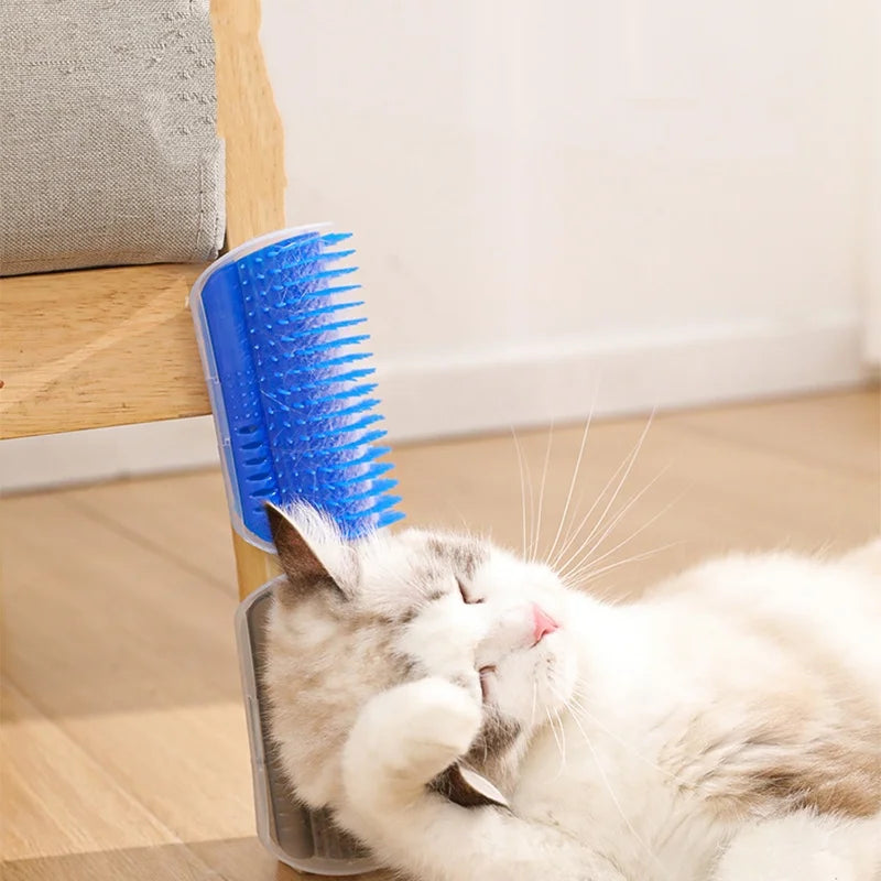 A white cat is relaxing and grooming itself using a blue self-grooming brush mounted on a wooden surface.