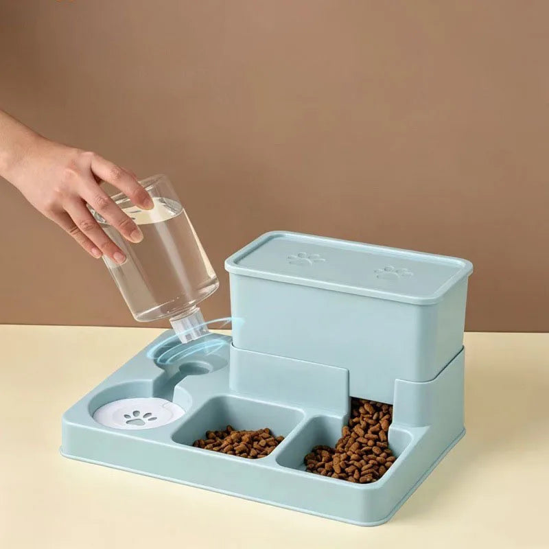 A hand pours water into a blue pet feeder and water fountain set on a light surface.