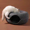 A white cat is resting inside a gray donut-shaped tunnel cat bed with an interactive play tube.