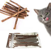 Eine graue Katze leckt ihre Lippen neben mehreren natürlichen Holzknochen für Katzen.