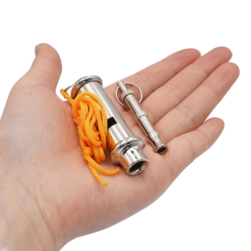 Eine Hand hält eine verstellbare Edelstahl-Trainierhupe mit einem leuchtend orangefarbenen Schnur.