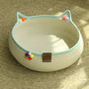 A beige cat scratcher and comfort bed with a light blue trim and colorful play balls.