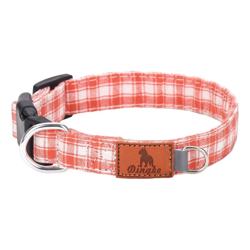 A plaid red and white fabric dog collar with a brown leather tag and silver buckle.