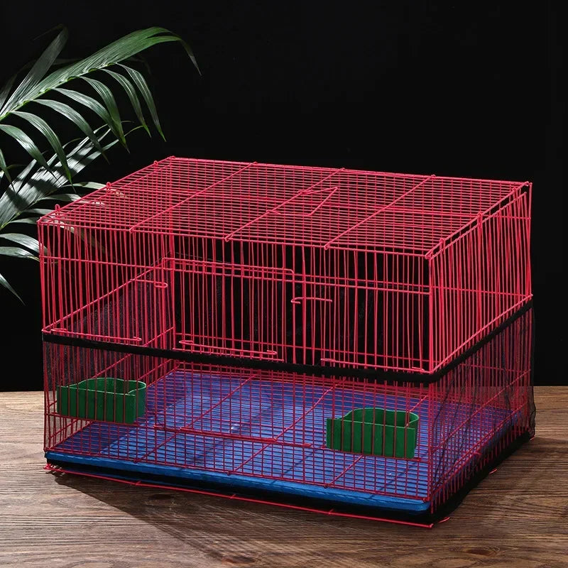A red wire bird cage with a blue base and green seed catchers resting on a wooden surface.