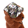 A brown teddy bear wearing a camouflage pet grooming visor cap with a white tag.
