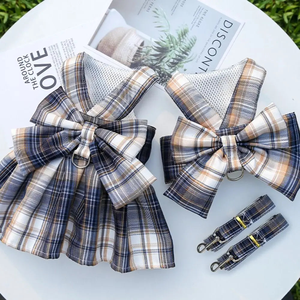 A plaid fabric bow and harness dress displayed on a white surface next to a magazine.