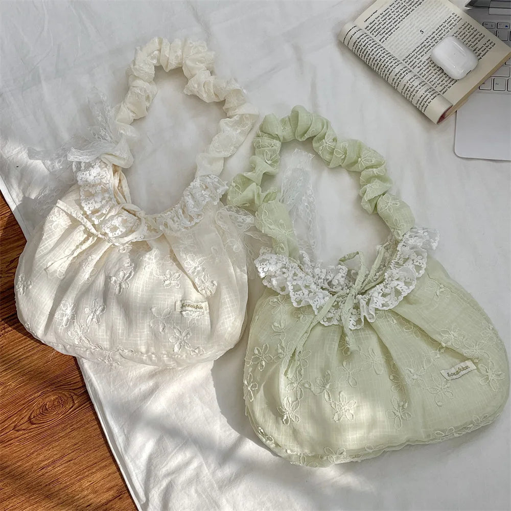 A pair of light green and white floral lace bowknot shoulder bags resting on a white cloth.