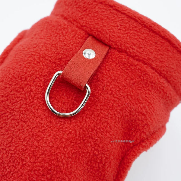 A close-up of a bright red fleece jacket with a leather D-ring leash attachment.