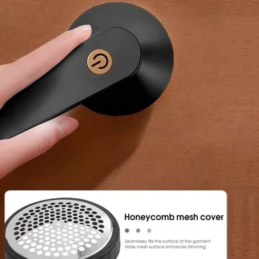 A hand is operating a black portable electric lint and fabric shaver with an LED display on a brown surface.