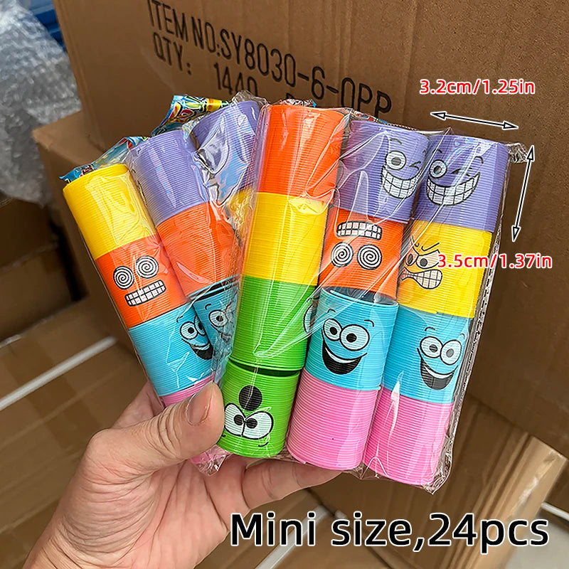 A hand holds a package of 24 mini spring coil toys in various bright colors and designs.