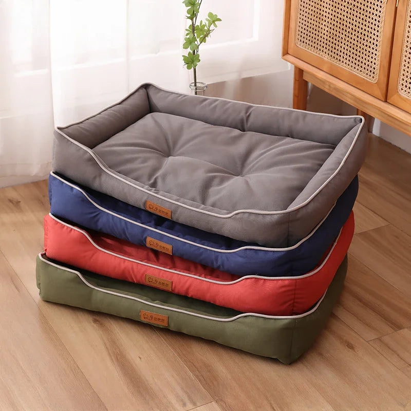 A stack of cozy faux fleece pet sofa beds in various colors, including gray, blue, and orange, resting on a wooden floor.