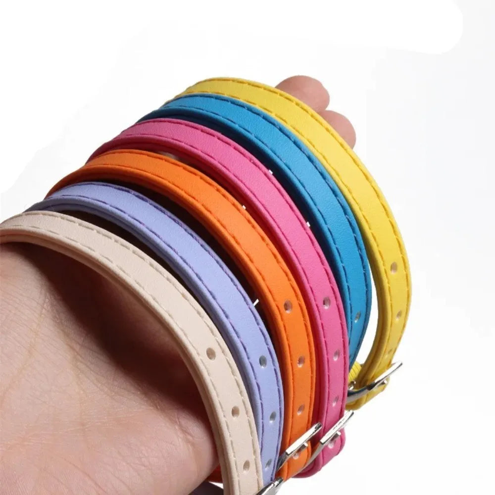 A hand holds a stack of colorful macaron cat collars made of soft PU leather and elastic webbing.