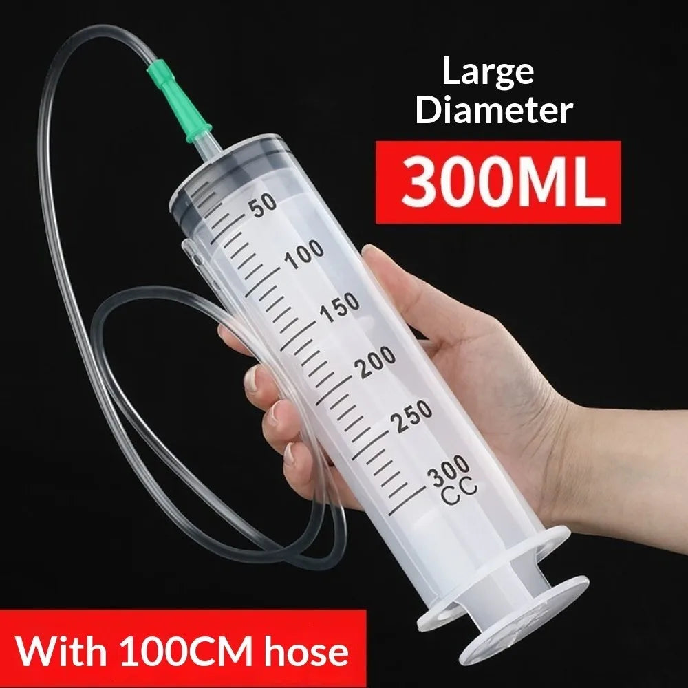 Eine Hand hält eine große 300ml Kunststoff-Spritze mit einer 100cm Schlauch für die Ölextraktion.