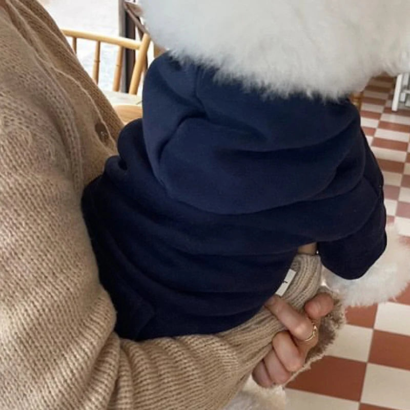Gros plan d'un sweat à capuche pour chien en polaire bleu marine, avec de la fausse fourrure blanche visible.