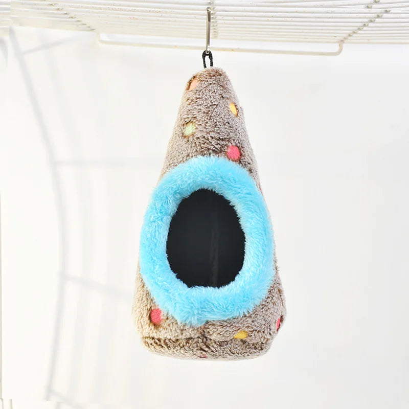 A fluffy, cone-shaped bird nest with a bright blue entrance is hanging from a wire grid.