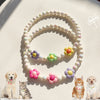 A set of pastel floral beaded pet collar necklaces displayed on a light background with small cats and a dog.