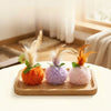 Three plush cat toys featuring orange, purple, and pink feathers on wooden trays