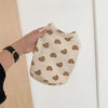 A light beige pet vest with a cartoon print of small brown bears on a person's hand.