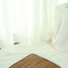 A fluffy white pet tent is displayed on a light-colored rug with a brown mat.