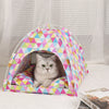 Lit de voyage pour chat à motif géométrique rose et multicolore sur une surface blanche.