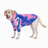 Un chien de couleur claire portant un sweat à capuche en polaire tie-dye rose et bleu.