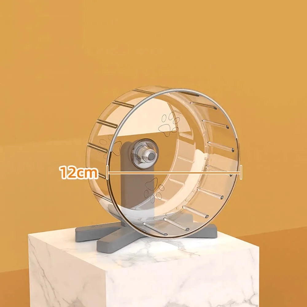 A transparent hamster exercise wheel with a silver frame and a clear plastic disk, displayed on a white marble surface.