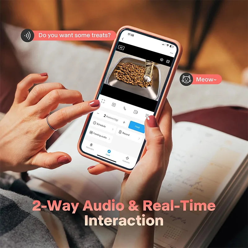 Hands hold a smartphone displaying an interface for a pet feeder, demonstrating 2-way audio and real-time interaction.