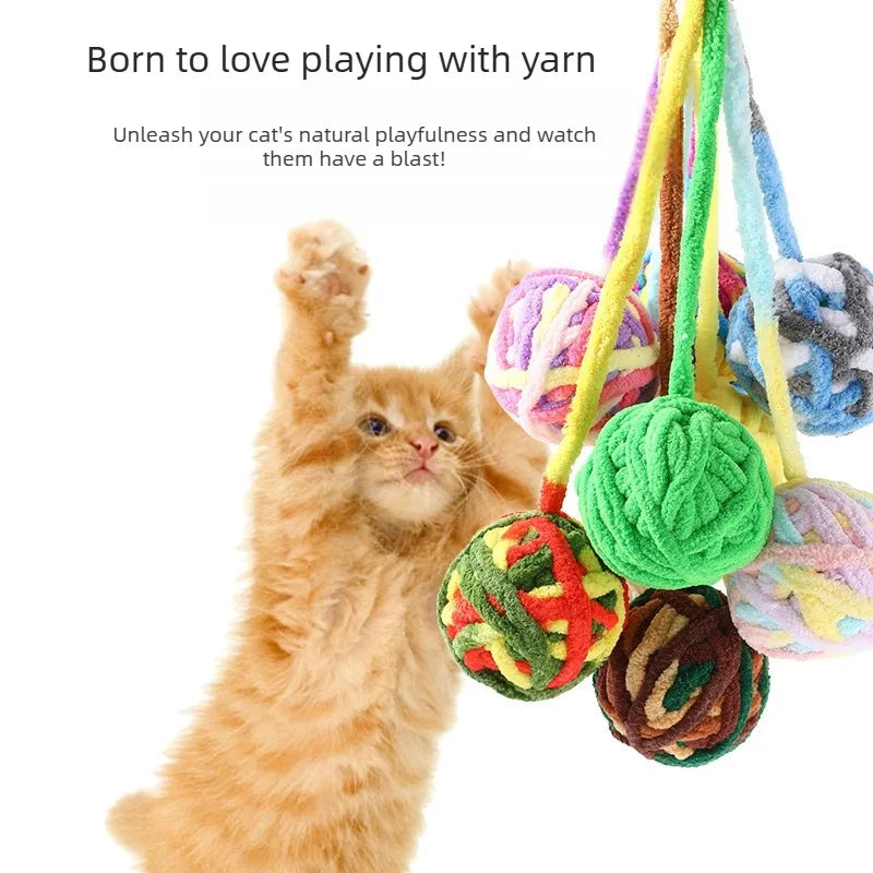 A fluffy orange kitten is playing with a colorful yarn ball toy.