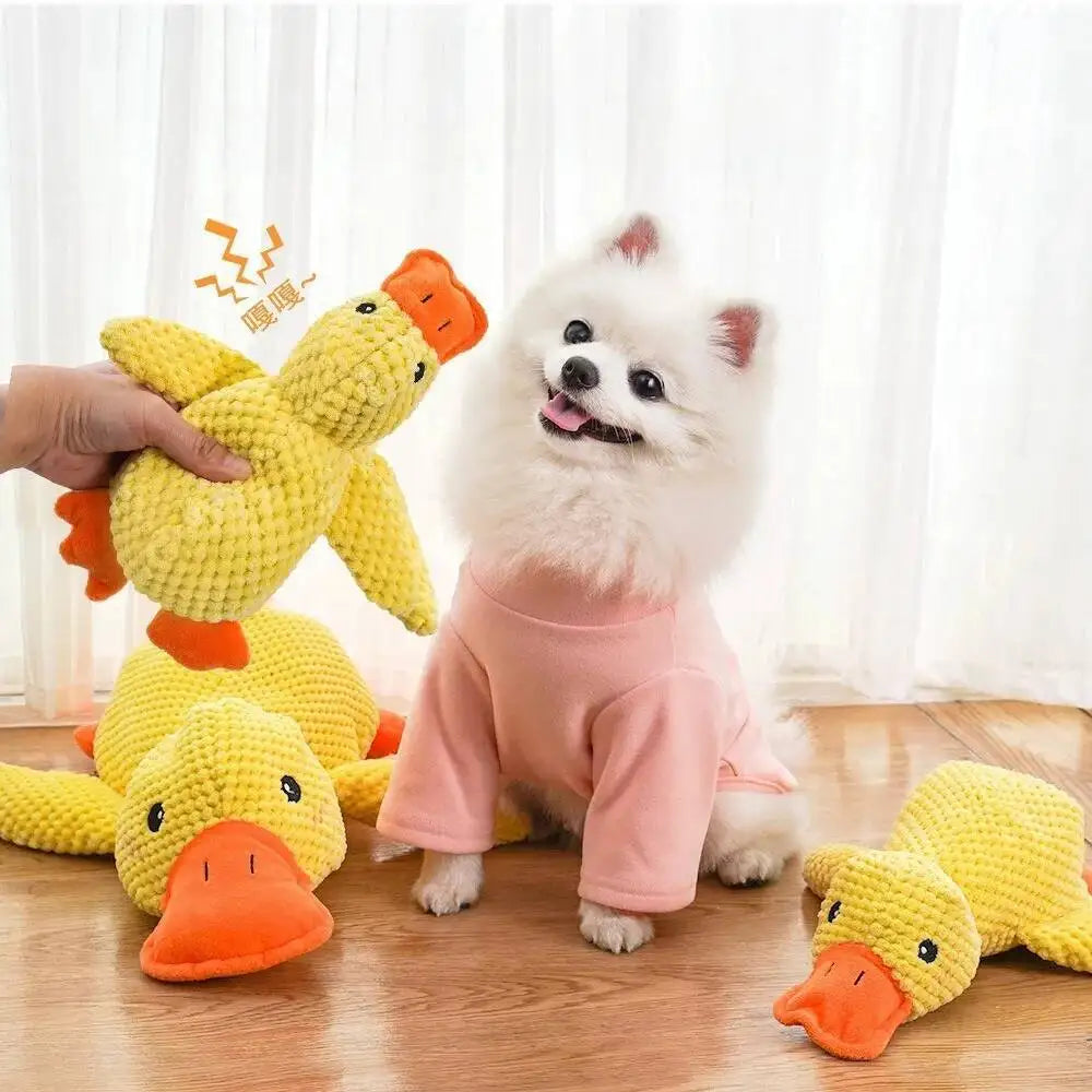 A fluffy white dog toy shaped like a duck, made of yellow plush fabric, is being held by a hand.