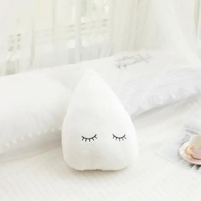 A white, star-shaped plush pillow with closed eyes rests on a white surface.