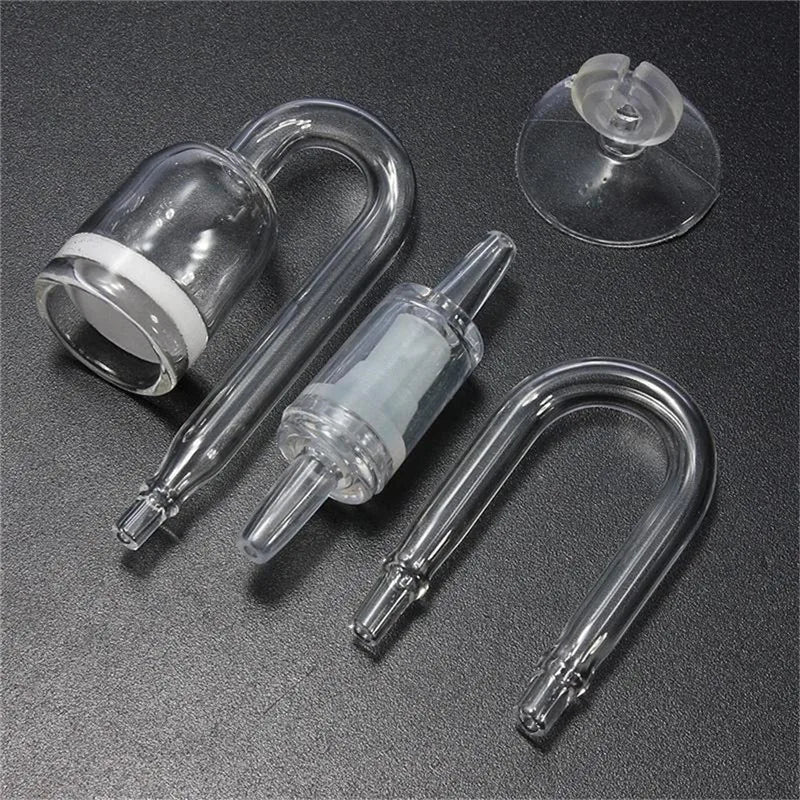 Un jeu de quatre composants de diffuseur d'eau pour aquarium en verre et plastique, incluant une vanne de sécurité.