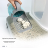 A hand is using a lightning shovel to sweep a smelly ball of pet waste into a gray plastic container.