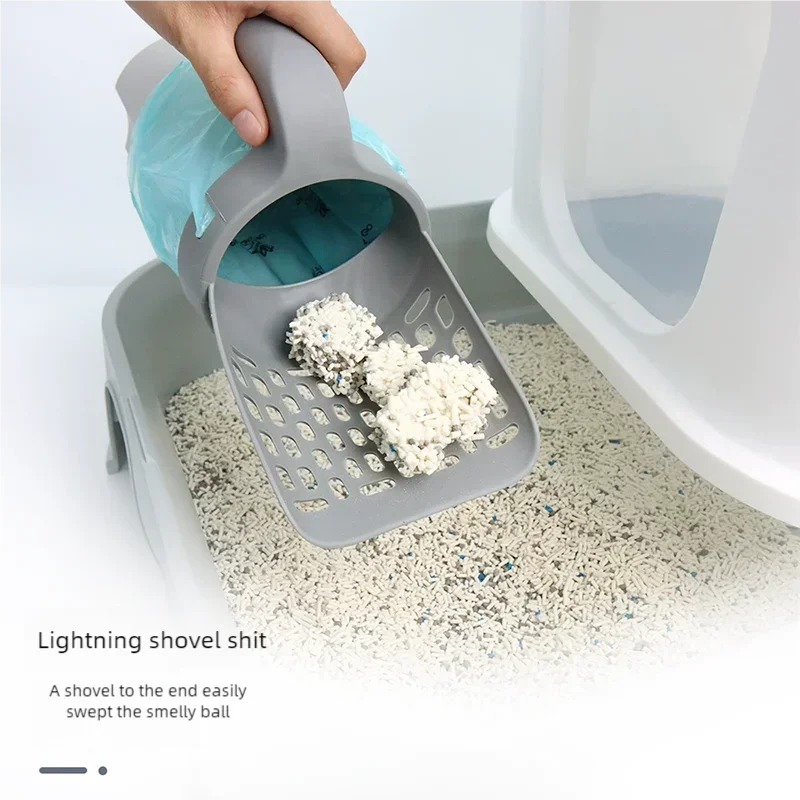 A hand is using a lightning shovel to sweep a smelly ball of pet waste into a gray plastic container.