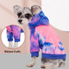 Un petit chien portant un sweat à capuche en polaire tie-dye avec des poignets côtelés.