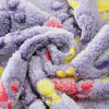 A close-up of a purple and gray fleece pet blanket with a paw print pattern, showing soft texture and folds.