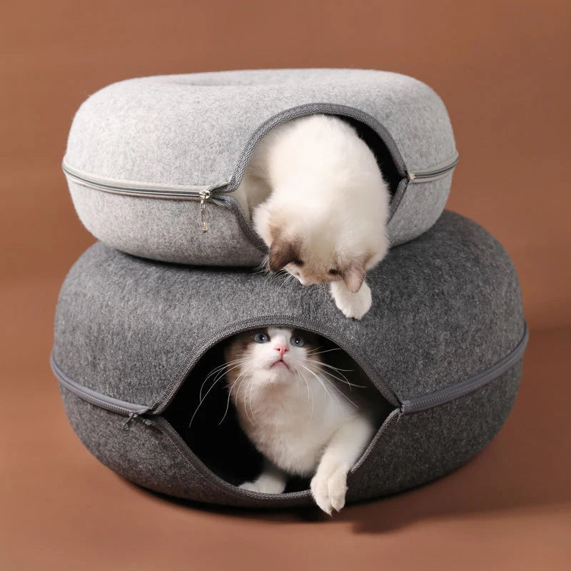 Deux lits pour animaux tricotés gris, un plus grand et un plus petit, avec des chats qui regardent depuis les ouvertures.