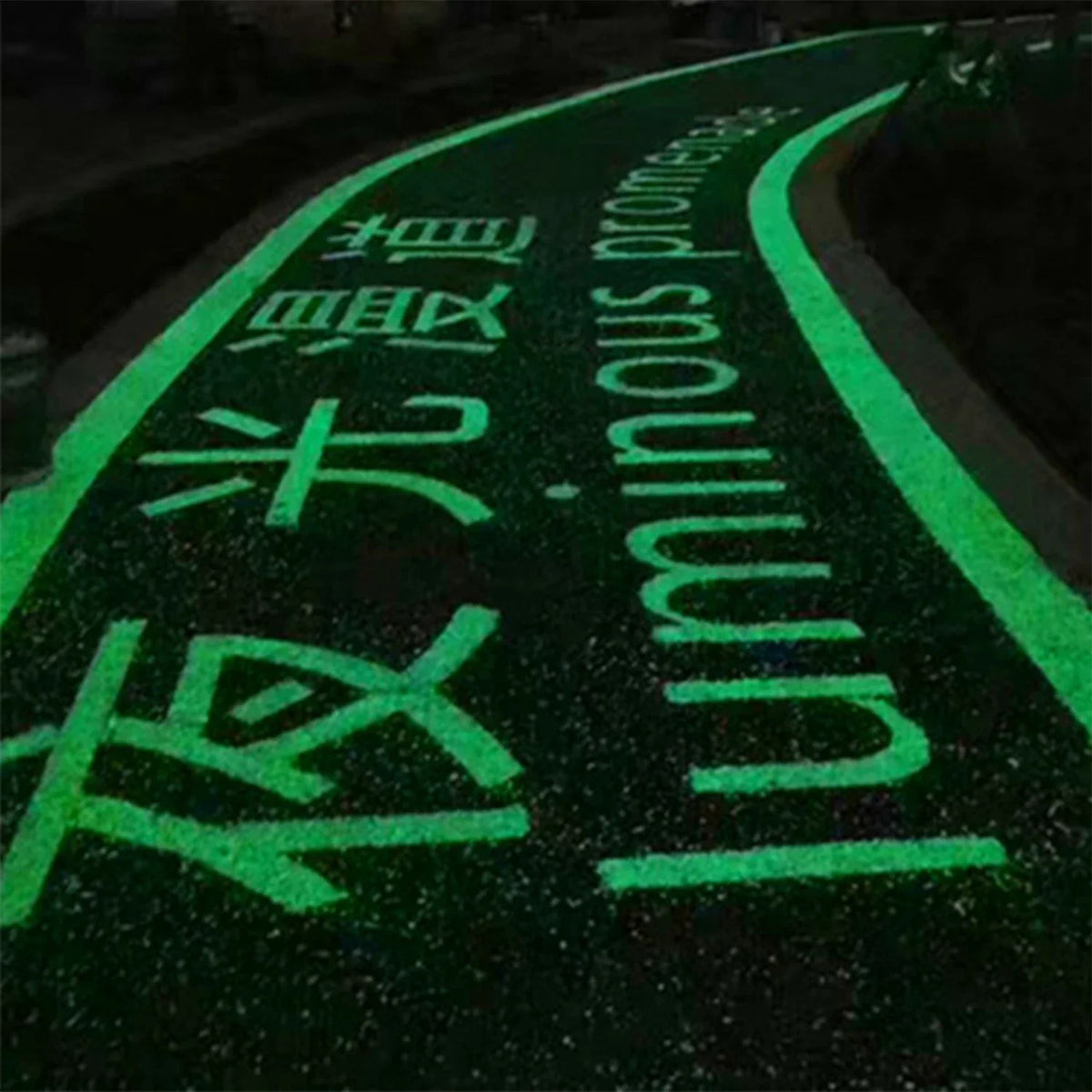 A dark road or path is marked with bright green glow-in-the-dark text and symbols on the asphalt.
