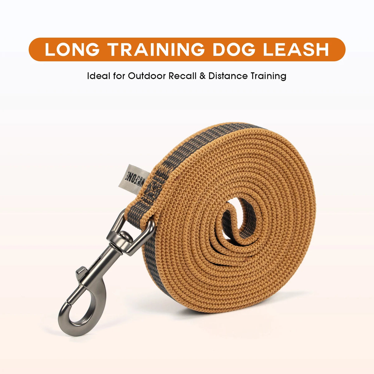 A coiled tan and black long training dog leash with a metal clip is shown against a white background.