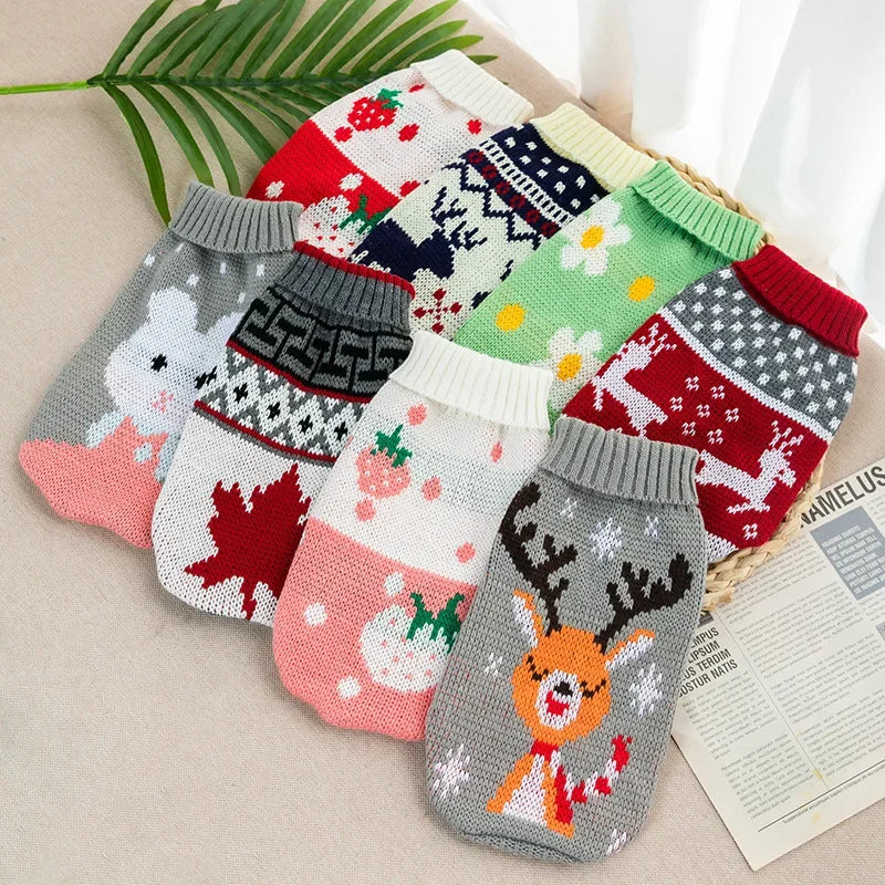 A collection of festive knitted dog sweaters in various patterns and colors laid out on a light surface.