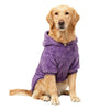 Un golden retriever portant un manteau d'hiver en polaire violet, assis et regardant directement l'appareil photo.