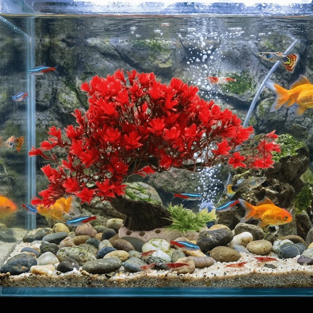 A vibrant red artificial pine tree plant is displayed in an aquarium setup with rocks and water.