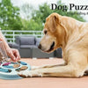 Un chien doré interagit avec un jouet distributeur de puzzle bleu, manipulé par une personne.