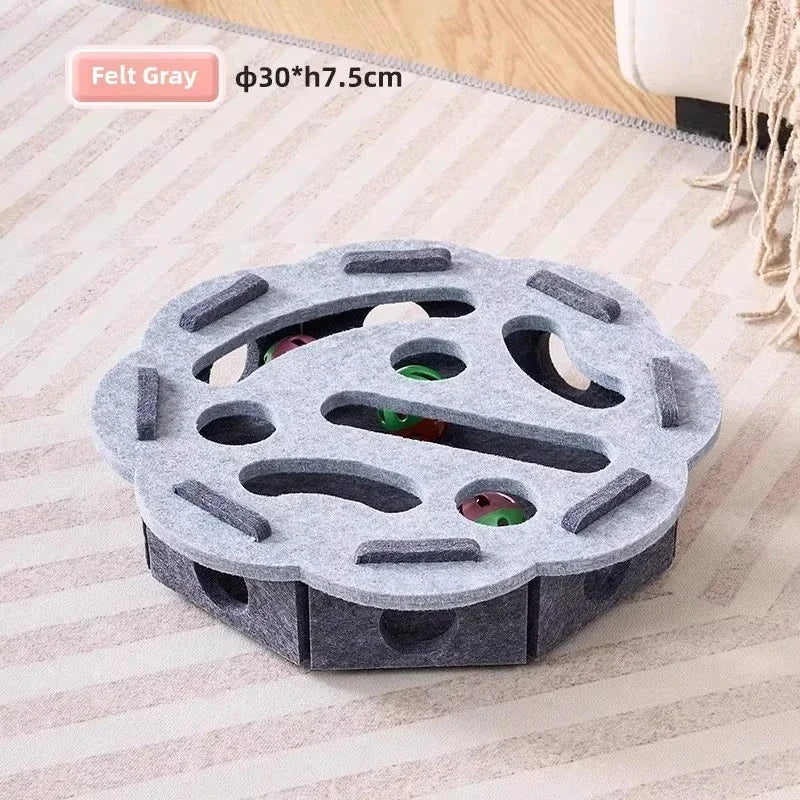 A gray felt puzzle toy for cats with multiple holes and colored balls resting inside.