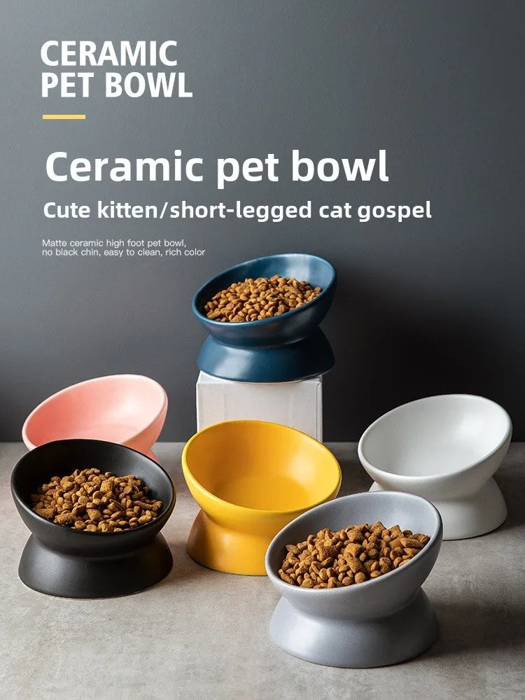 A collection of matte ceramic pet bowls in various colors, including blue, yellow, and white, displayed on a gray surface.