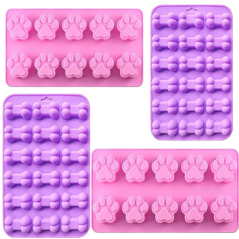 A set of silicone molds shaped like dog paws and bones in pink and purple colors.