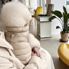 Ein flauschiger beiger Wintermantel für Haustiere liegt auf einer weißen Decke.