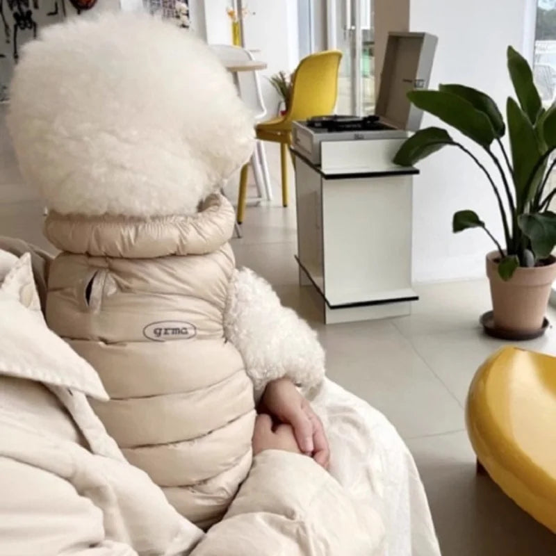 Ein flauschiger beiger Wintermantel für Haustiere liegt auf einer weißen Decke.