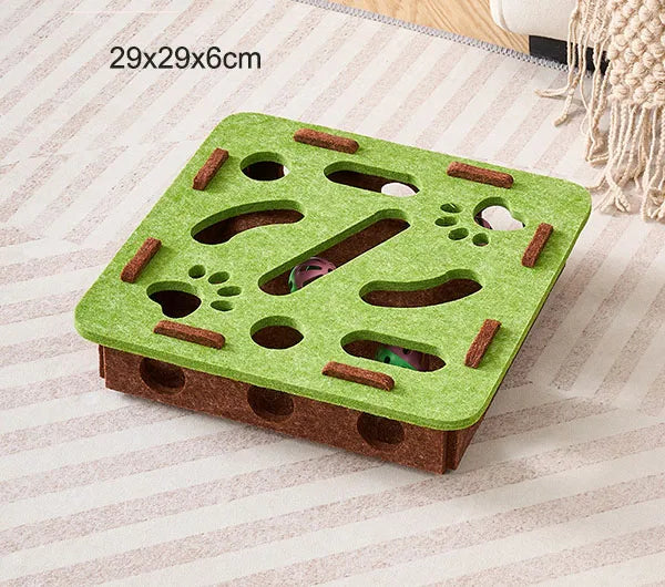 Labyrinthe de puzzle en feutre vert pour chats avec des trous et une cloche, emballé dans du carton brun.