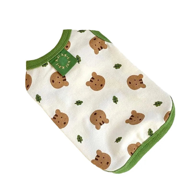 A white dog vest with a bear print featuring small brown paw prints and green trim.