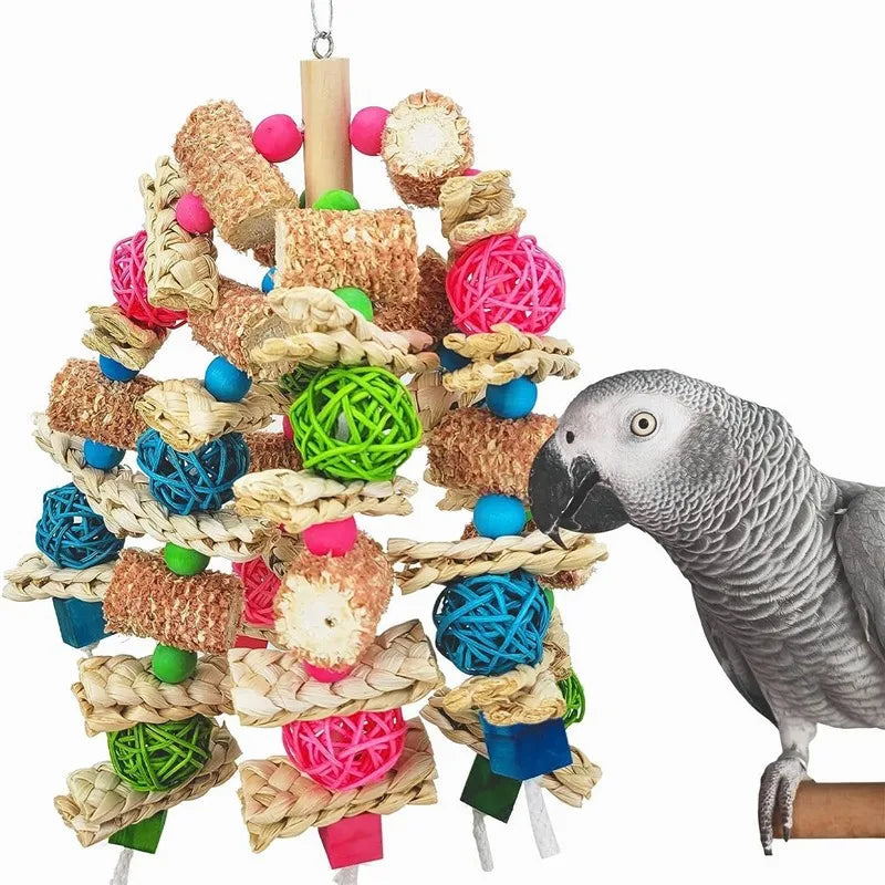 A gray parrot is interacting with a natural wooden parrot bite toy made of woven straw and colorful foam pieces.